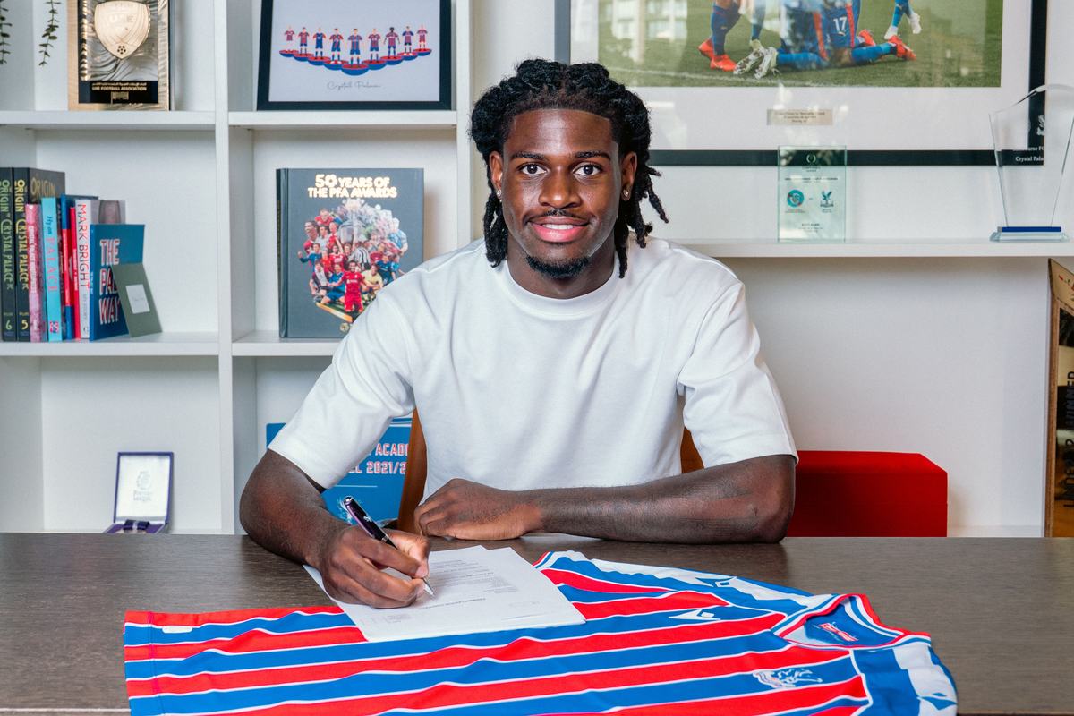 Player signing a contract at a desk with a Crystal Palace shirt laid out in front of him