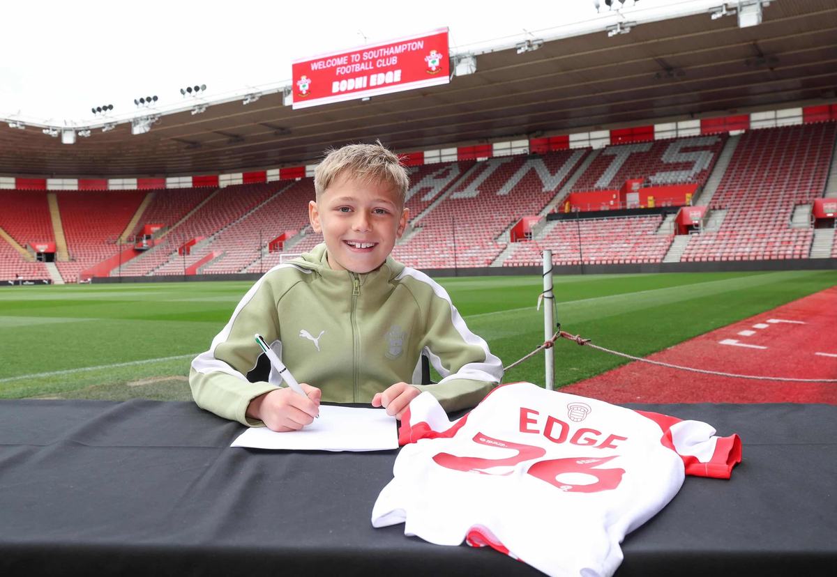 Young player signing inside Southampton’s stadium with a shirt on the table