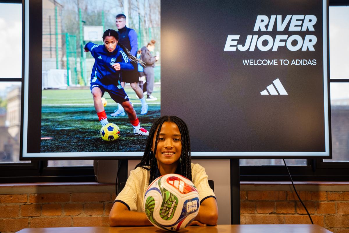 Young player sitting behind a football beneath a Welcome to adidas screen