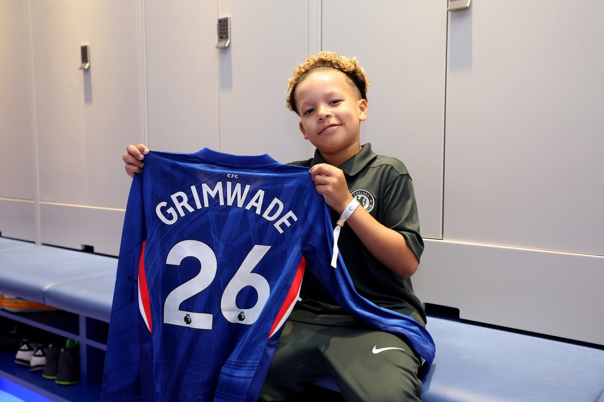Young player holding up a Chelsea shirt in the changing room