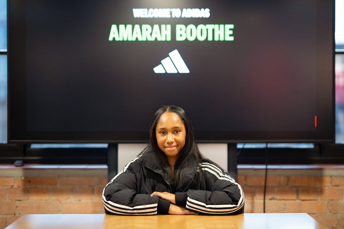 Young player sitting at a table beneath a Welcome to adidas screen