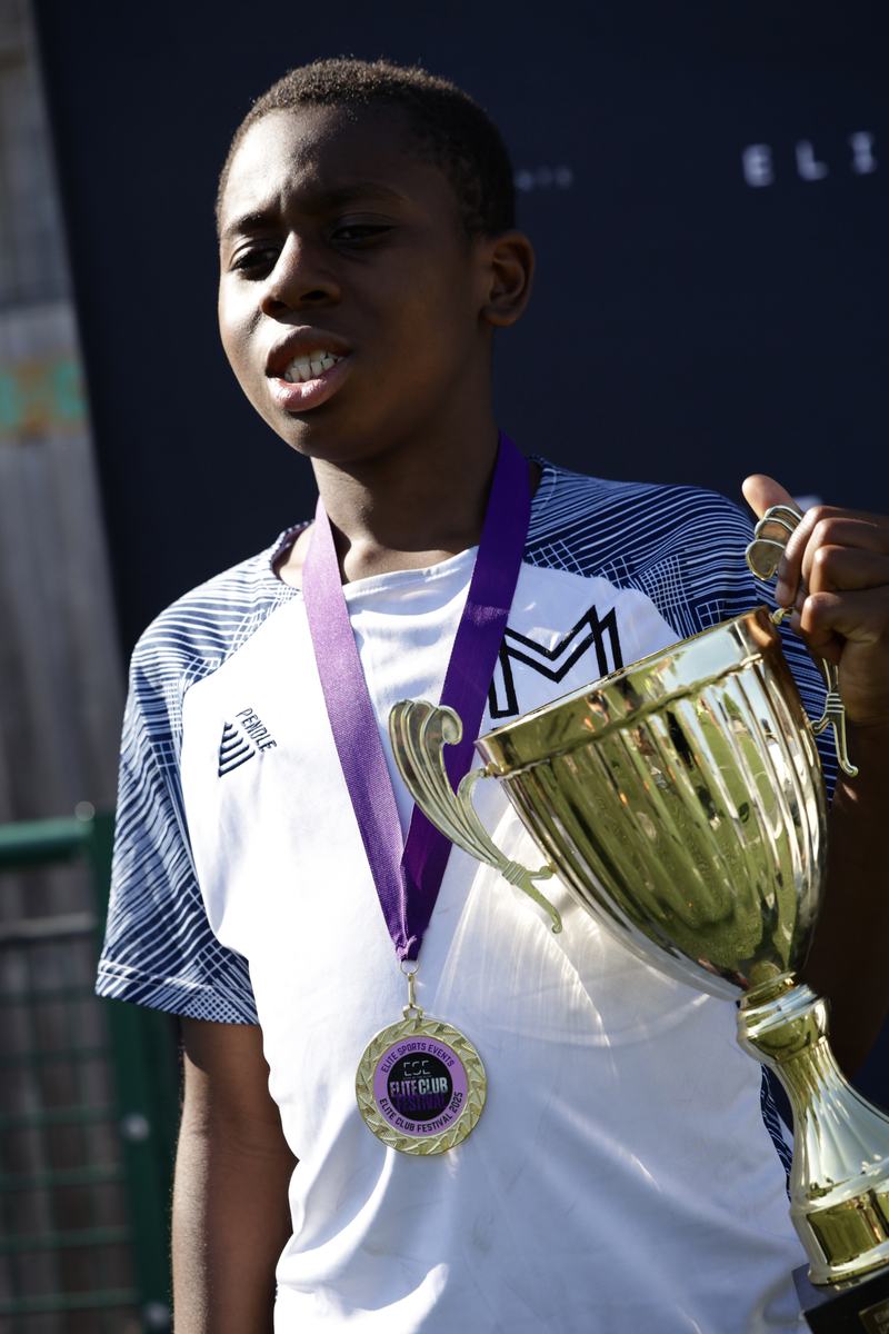 Player wearing a medal and holding a gold trophy