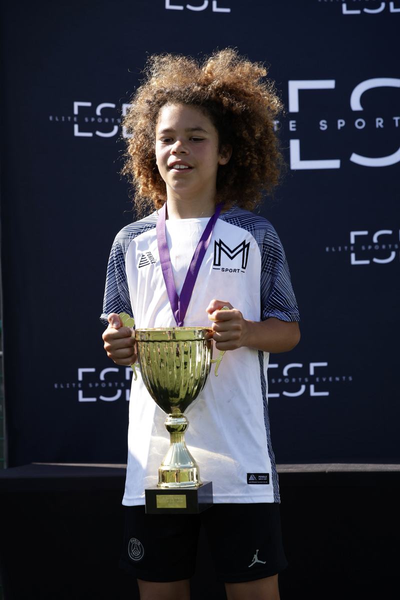 Player wearing a medal and holding a gold cup